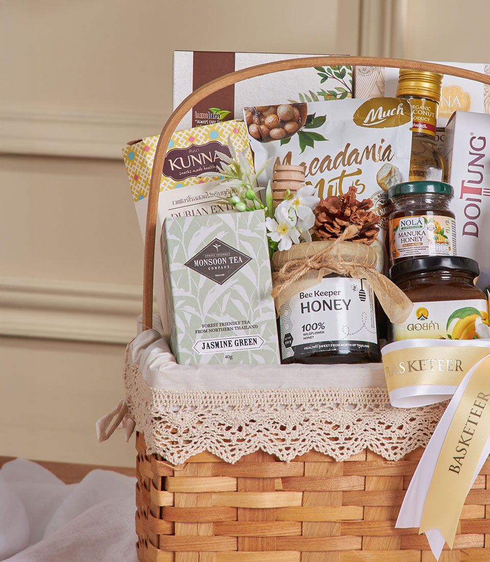 Organic Thai wellness gift basket with jasmine green tea, manuka honey, macadamia nuts, and artisan snacks in woven natural
