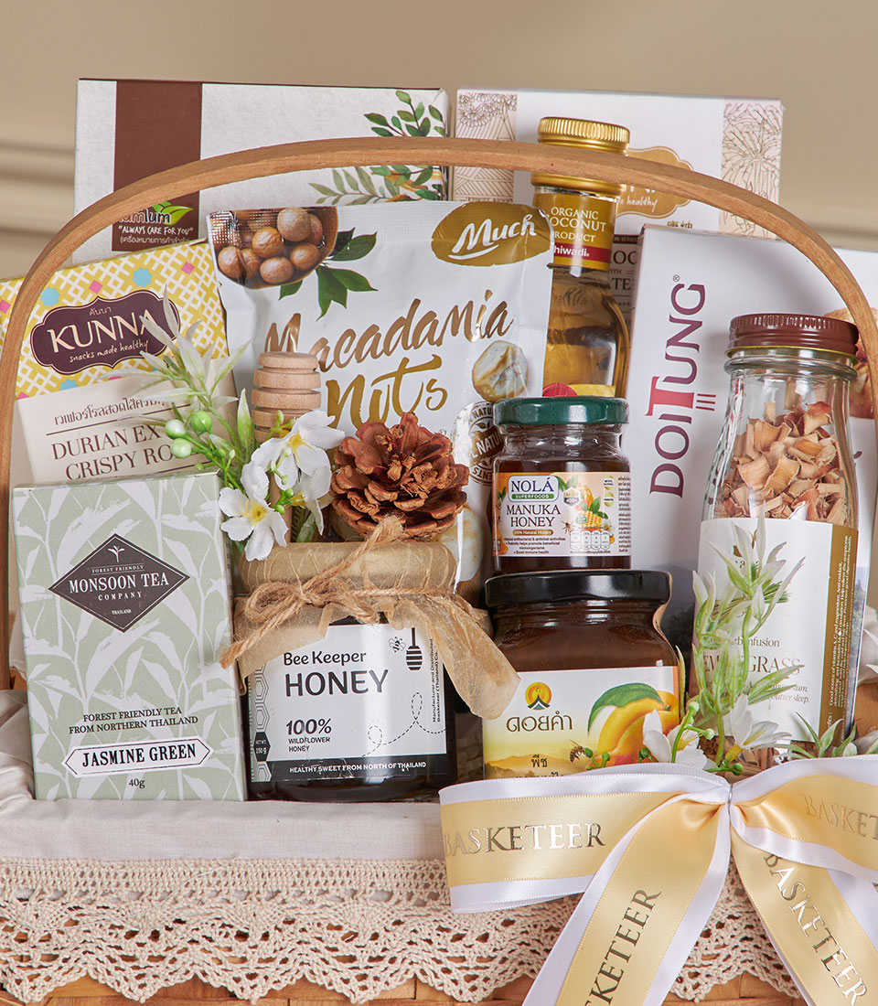 Organic Thai wellness gift basket with macadamia nuts, jasmine green tea, manuka honey, and coconut products in woven wooden