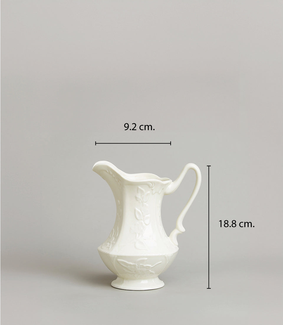 Embossed white ceramic pitcher with floral patterns, 18.8 cm height, elegant footed base and curved handle