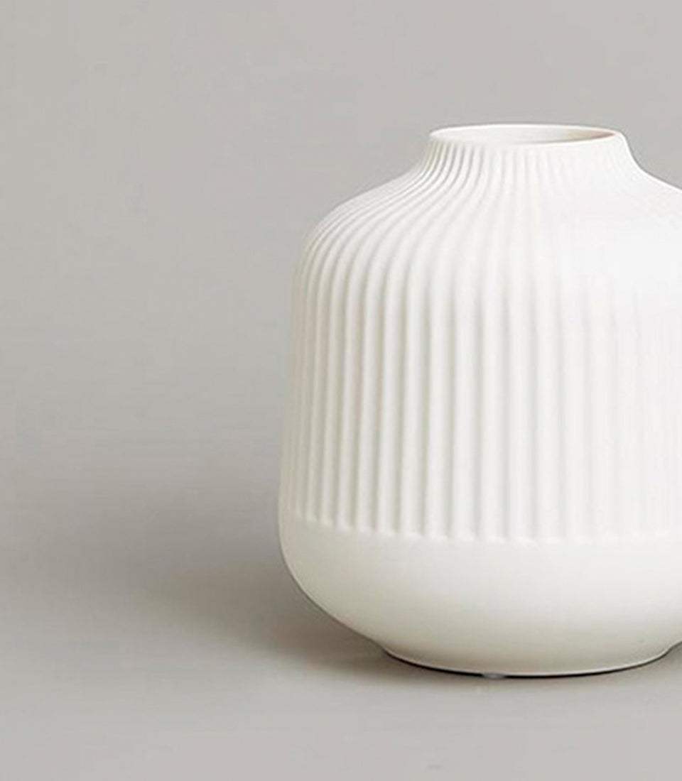 Minimalist white ribbed ceramic vase with rounded base and tapered neck