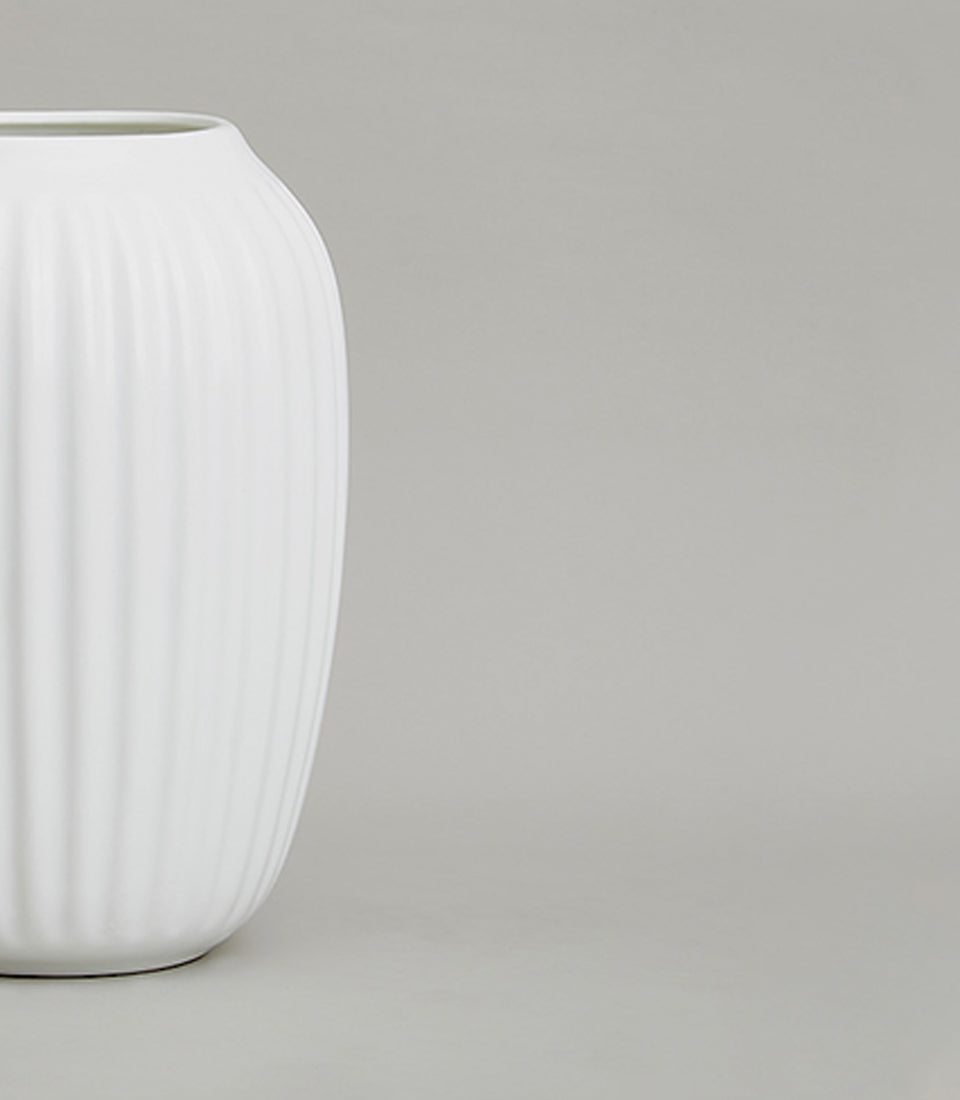 Minimalist white ribbed ceramic vase with vertical fluted texture and curved oval form