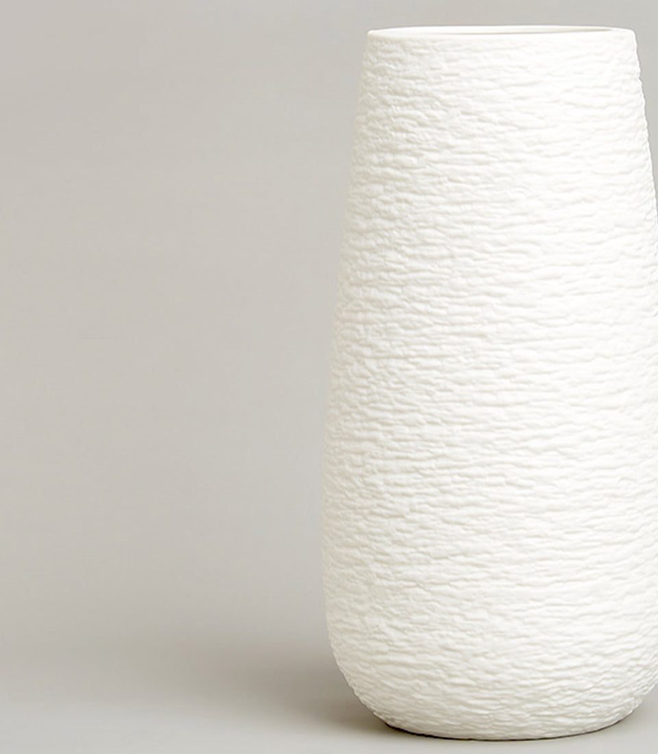 Tall white ceramic vase with rippled textured surface and tapered cylindrical shape