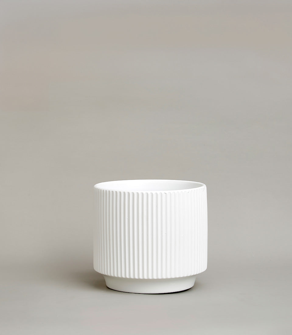 White ceramic vase with vertical ribbed texture and minimalist design
