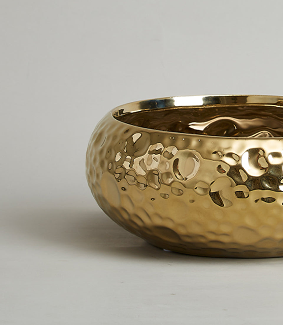 Hammered gold ceramic bowl with reflective polished finish and textured dimpled surface