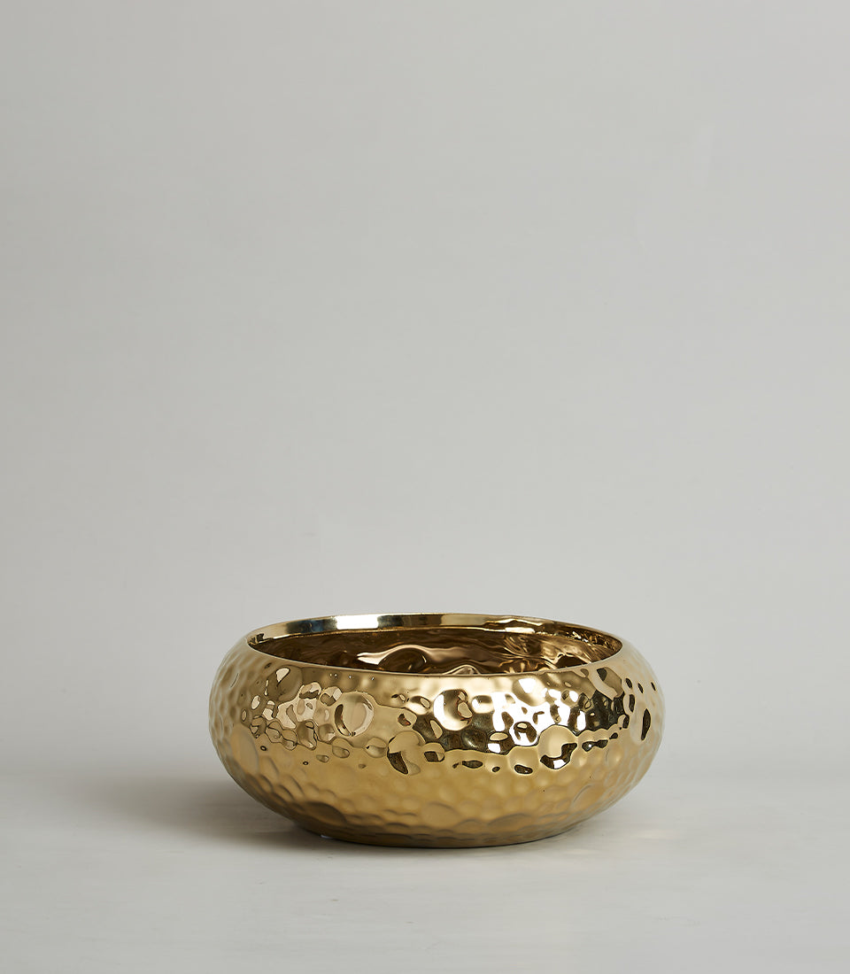 Gold hammered ceramic bowl with reflective metallic finish and artisan dimpled texture