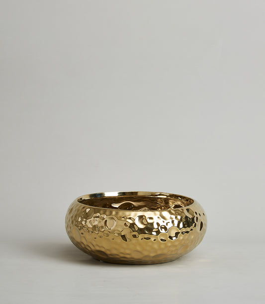 Gold hammered ceramic bowl with reflective metallic finish and artisan dimpled texture