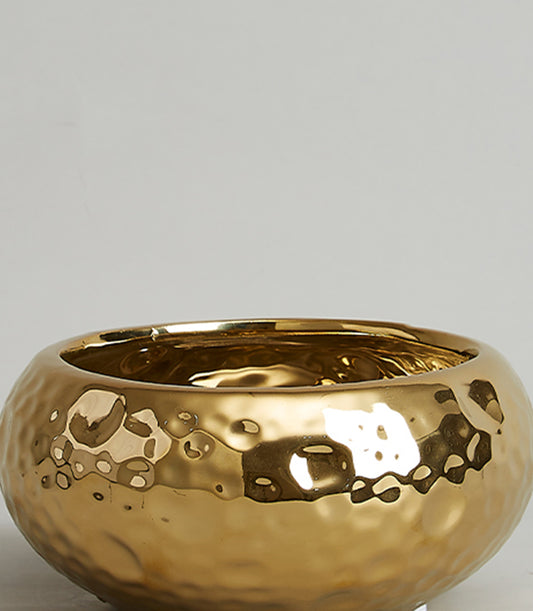 Gold hammered ceramic bowl with reflective metallic finish and dimpled texture