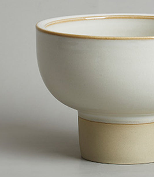 Cream and beige ceramic pedestal bowl with rustic brown rim detail