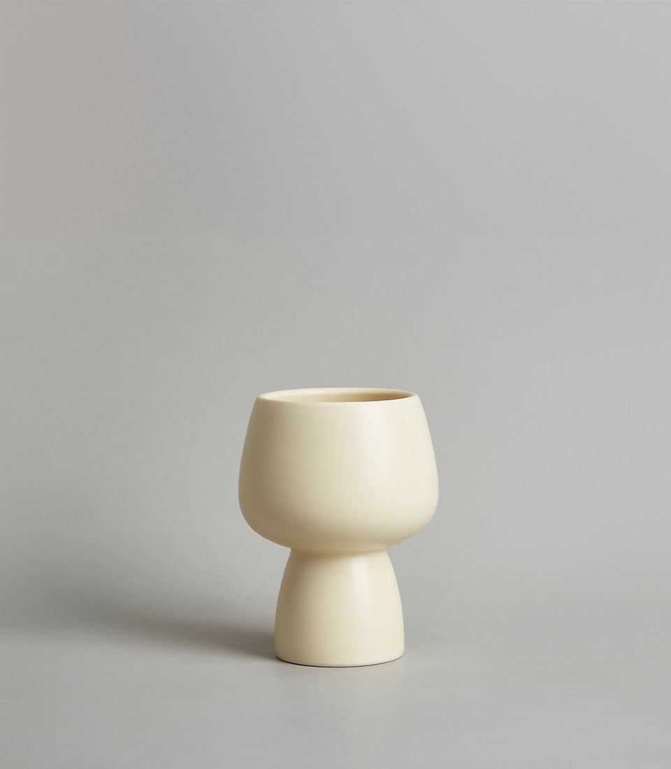 Cream ceramic chalice vase with rounded bulbous body and narrow cylindrical base
