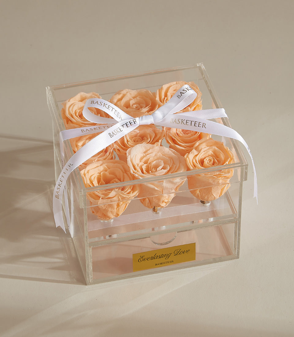 Luxury preserved peach roses in clear acrylic box with white ribbon bow, everlasting gift arrangement