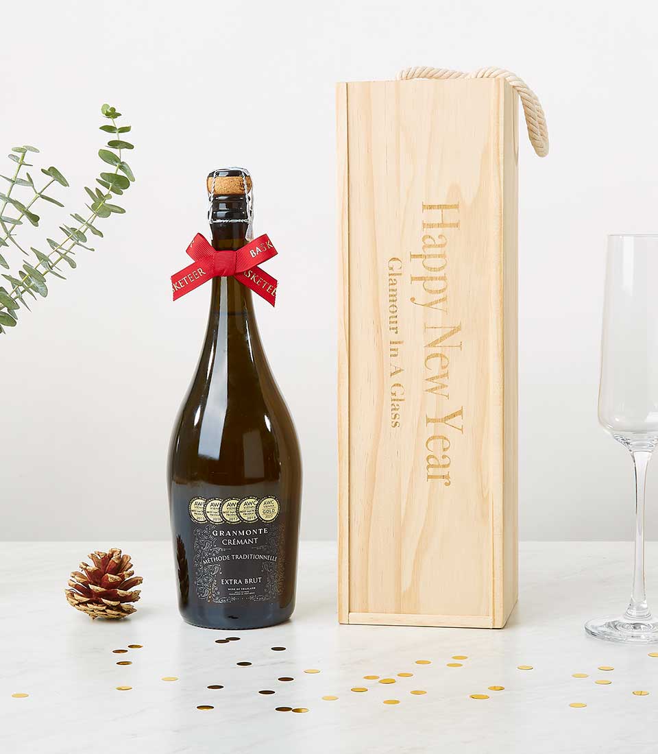 Award-winning Crémant sparkling wine with gold seals in wooden gift box, red ribbon, champagne flute, and festive holiday