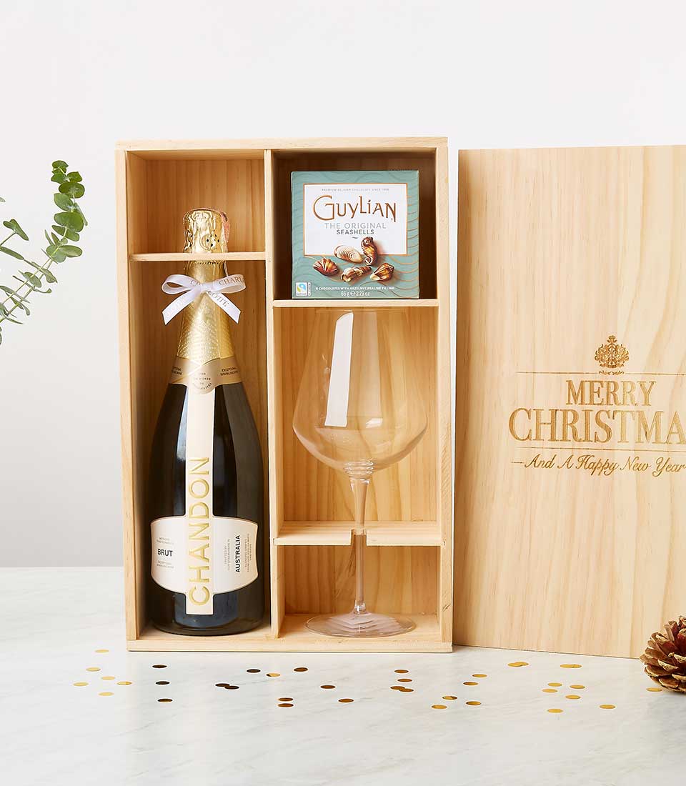 Light wooden wine gift box with Chandon sparkling wine, chocolates, and stemmed glass, festive holiday presentation