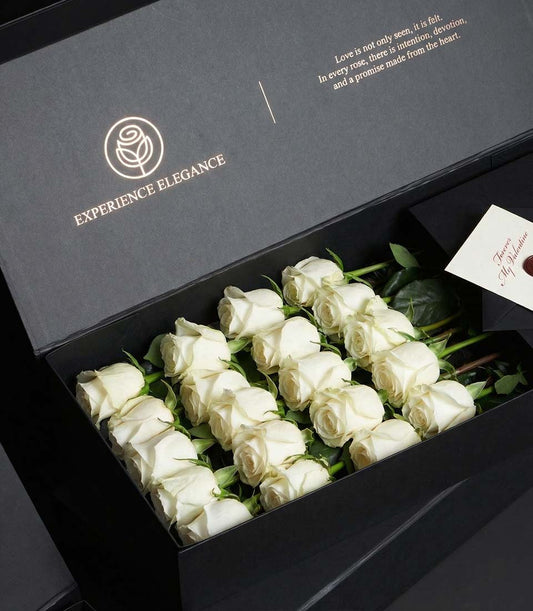 Luxury white rose bouquet in dark matte gift box with gold-foil logo and Valentine's Day message card