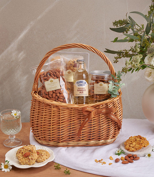 Wicker basket with artisan almond cookies, roasted nuts, ginger ale, and almond brittle gift hamper