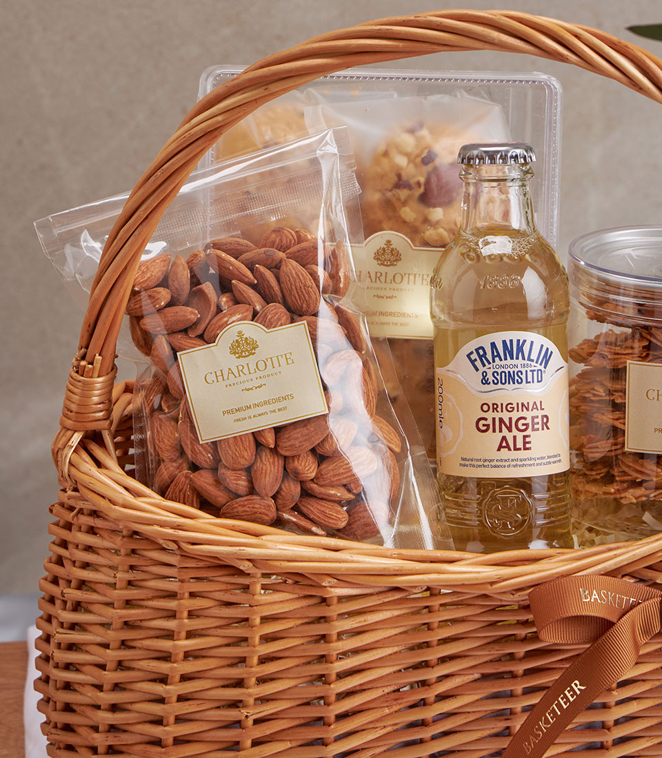 Woven wicker basket with almond cookies, gourmet nuts, and ginger ale gift set