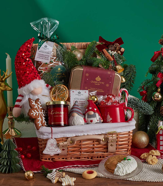 Festive Christmas gift hamper with gingerbread cookies, scented candle, ceramic gnomes, and holiday decorations in woven