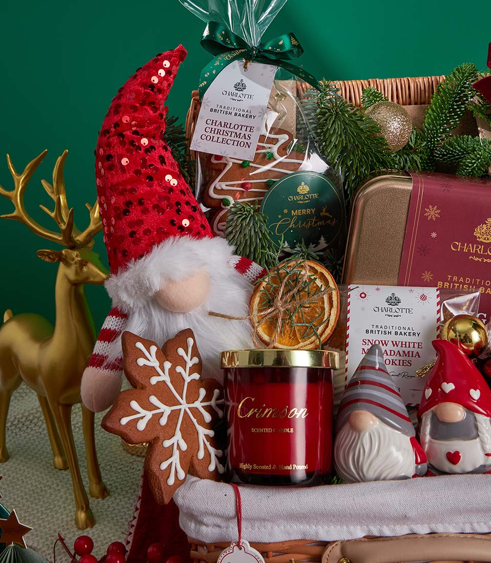 Festive Christmas gift basket with plush gnome, gingerbread cookies, Crimson scented candle, and gold ornaments in wicker