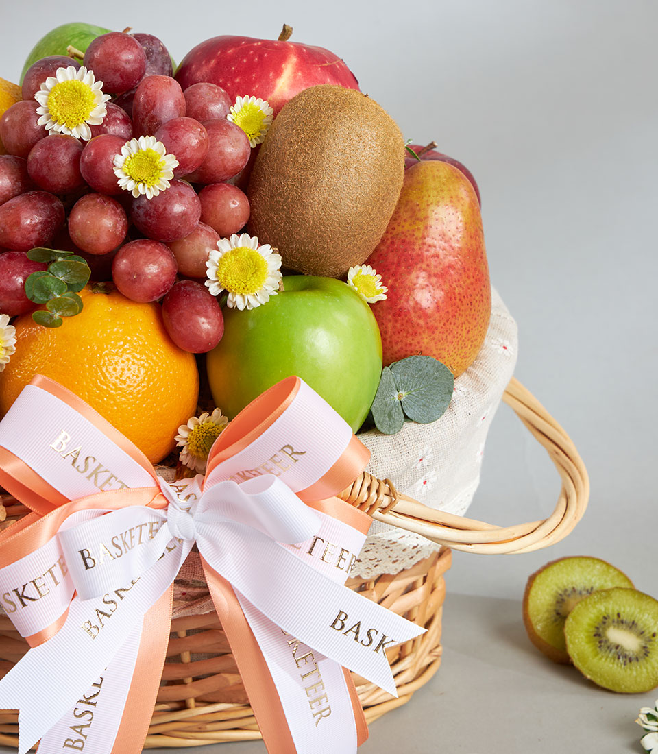 Classic woven fruit basket with Granny Smith apple, grapes, pear, and fresh citrus tied with peach ribbon