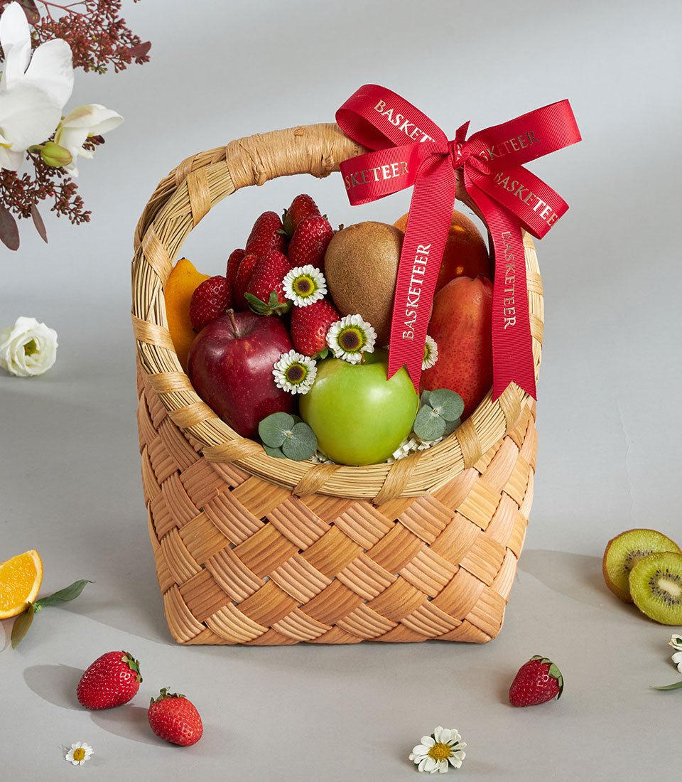 Premium wicker fruit basket with red apples, strawberries, kiwi and fresh florals, tied with red ribbon