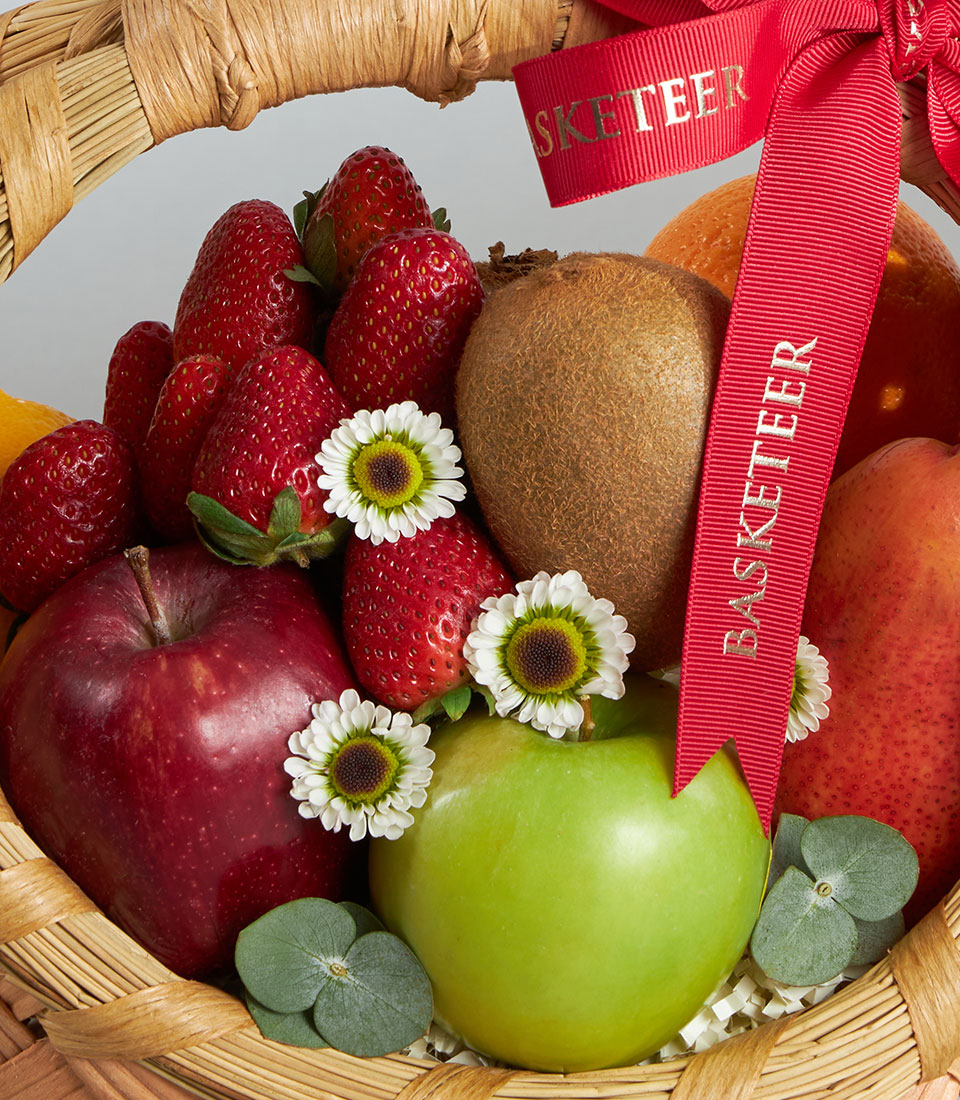 Premium wicker fruit basket with fresh strawberries, Dazzle apples, and imported fruits nestled with daisies