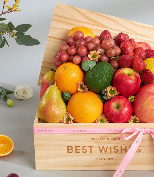 Premium fresh fruit wooden gift box with red apples, oranges, strawberries, grapes and pears, tied with pink ribbon