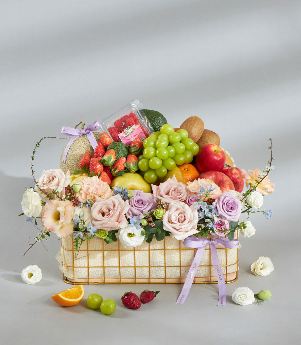 Luxury gold wire fruit and flower basket with fresh strawberries, grapes, citrus, and pastel pink and lavender roses