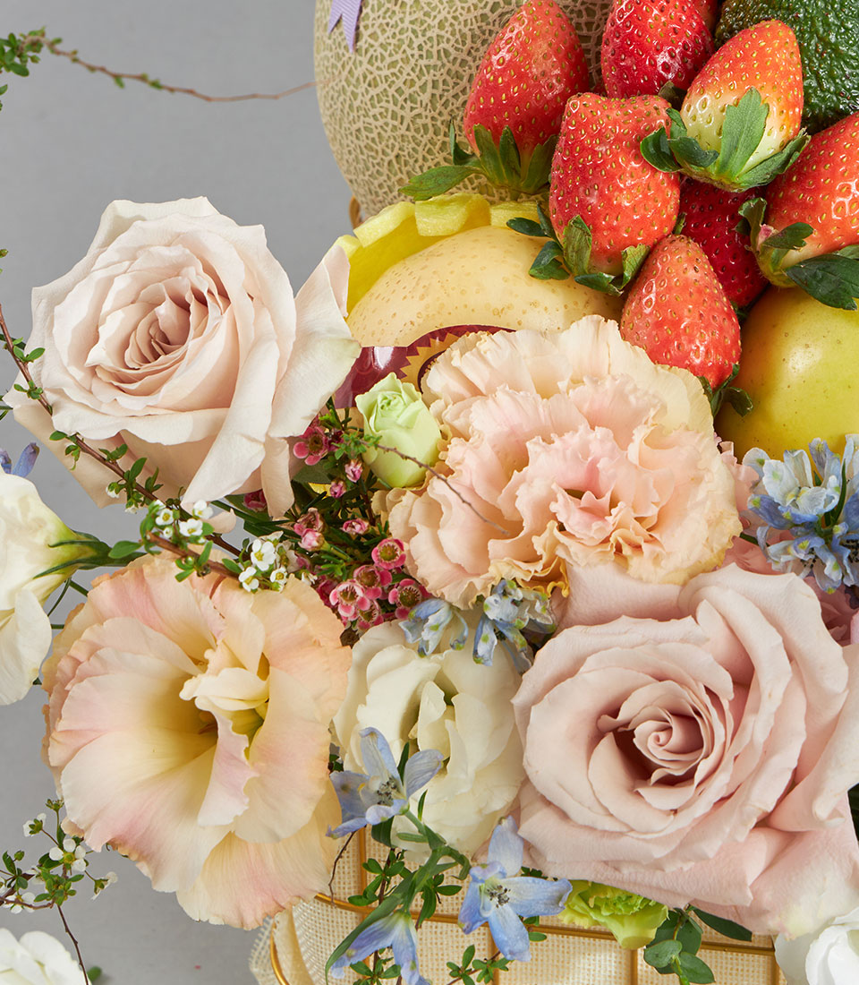 Luxury fruit and pastel flower basket with fresh roses, strawberries, melon, and cream blooms in burlap wrap
