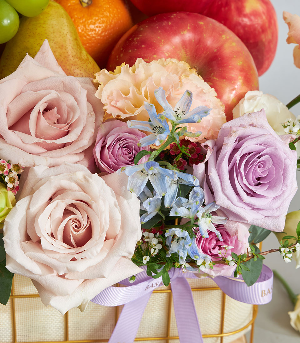 Luxury fruit and pastel flower basket with roses, delphiniums, and fresh seasonal fruits in gold wire basket