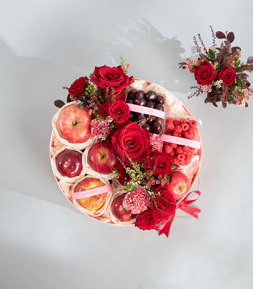 Luxury round gift basket with fresh red apples, raspberries, cherries, and deep red roses for birthday celebrations