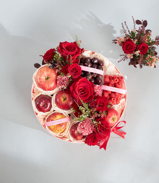 Luxury round gift basket with fresh red apples, raspberries, cherries, and deep red roses for birthday celebrations