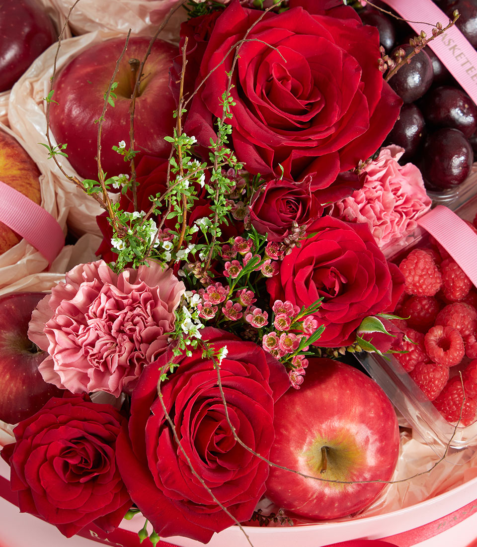 Luxury red fruit and floral round gift box with roses, carnations, fresh apples, cherries and raspberries for birthdays