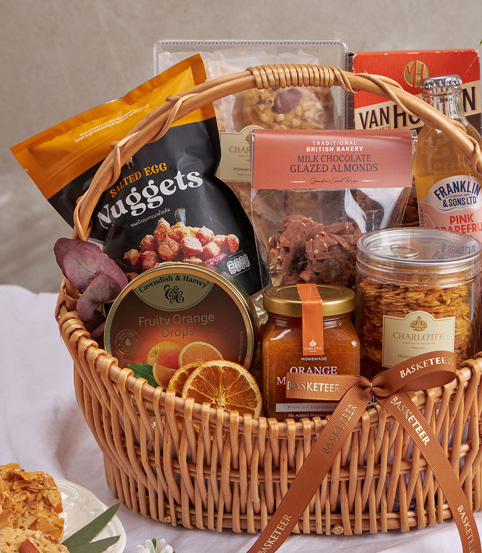 Curated gourmet gift basket with salted egg nuggets, milk chocolate almonds, orange drops, and pink grapefruit soda in