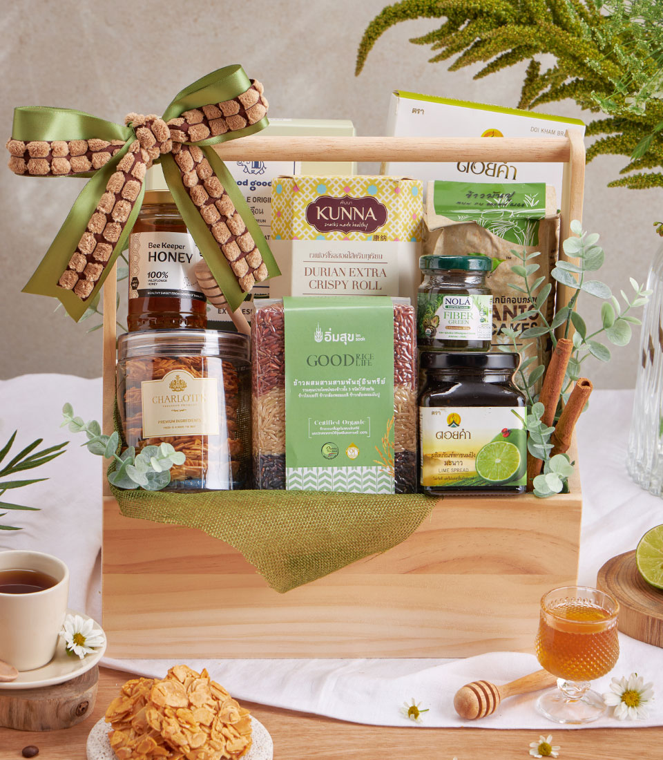 Wooden gift basket with organic rice, honey, lime spread, durian crisps, and wellness snacks tied with green ribbon
