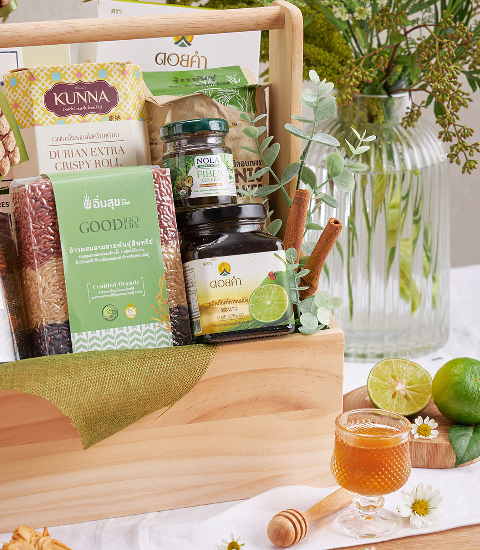 Wooden gift basket filled with organic rice, durian rolls, fiber supplement, and lime spread with fresh lime, daisies, and