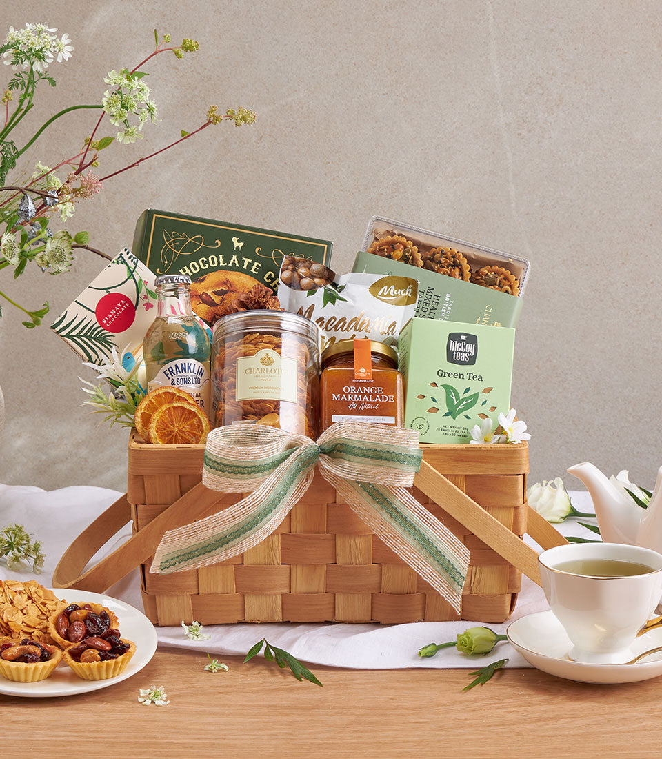 Premium gift hamper with chocolate chip cookies, macadamia nuts, green tea, and gourmet treats in wicker basket