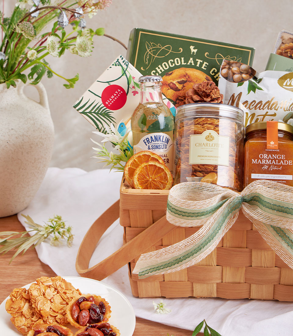 Luxury gift basket with chocolate, macadamia nuts, green tea, and gourmet treats in woven wood