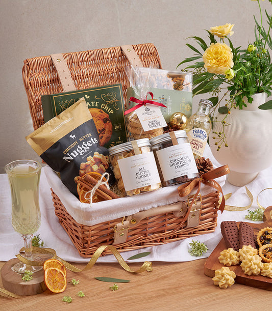Wicker picnic basket filled with premium butter cookies, chocolate shortbread, ginger ale, and artisan British baked goods