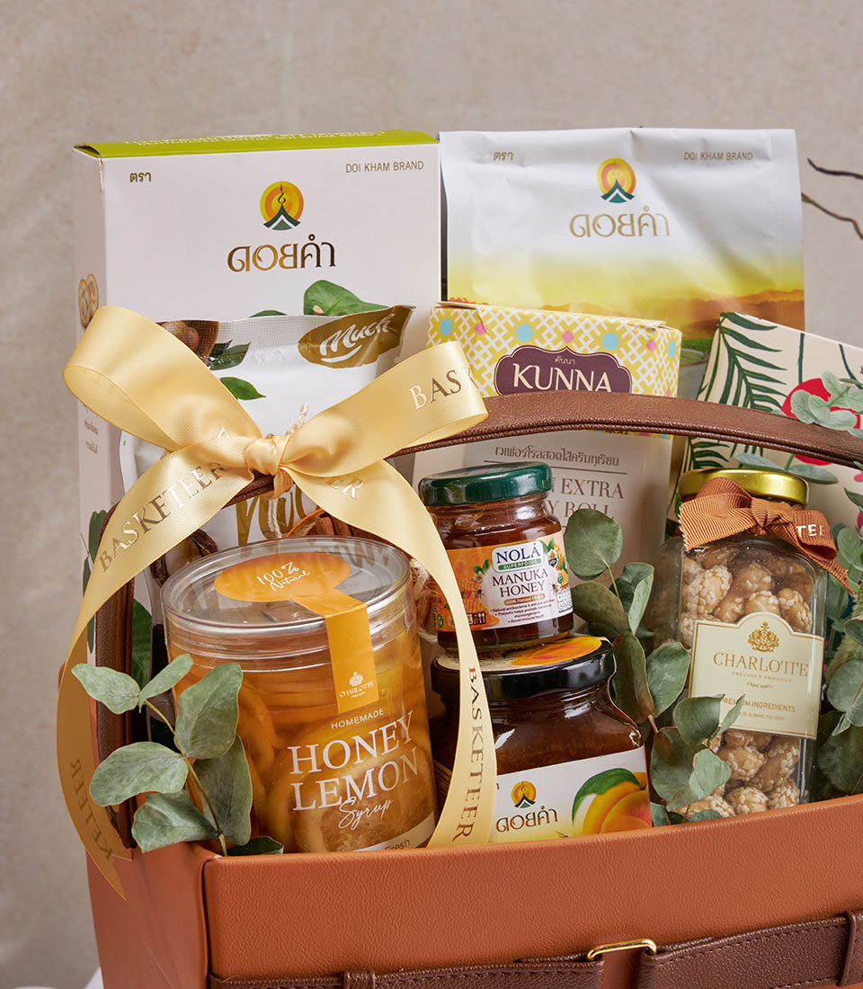Premium wellness gift basket with honey, syrups, and gourmet treats in brown leather-finish packaging with gold ribbon bow