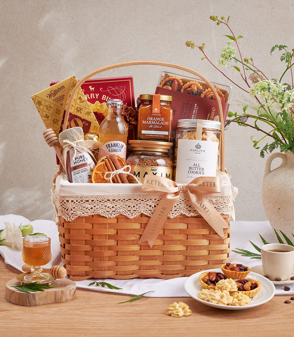 Luxury gourmet gift basket with raspberry cookies, lychee honey, chocolate, and artisan treats in woven wicker