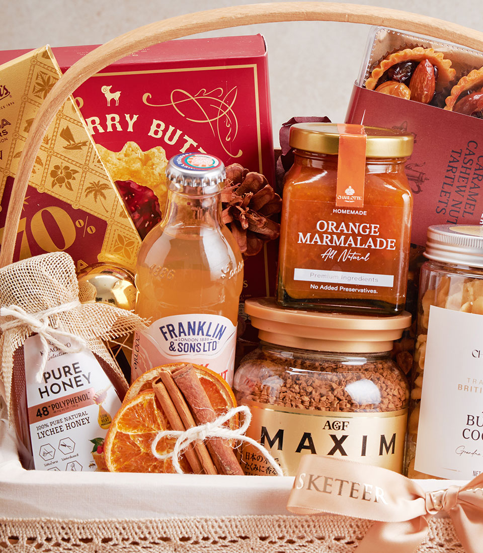 Gourmet gift hamper with raspberry cookies, lychee honey, chocolate, and artisan provisions in woven basket