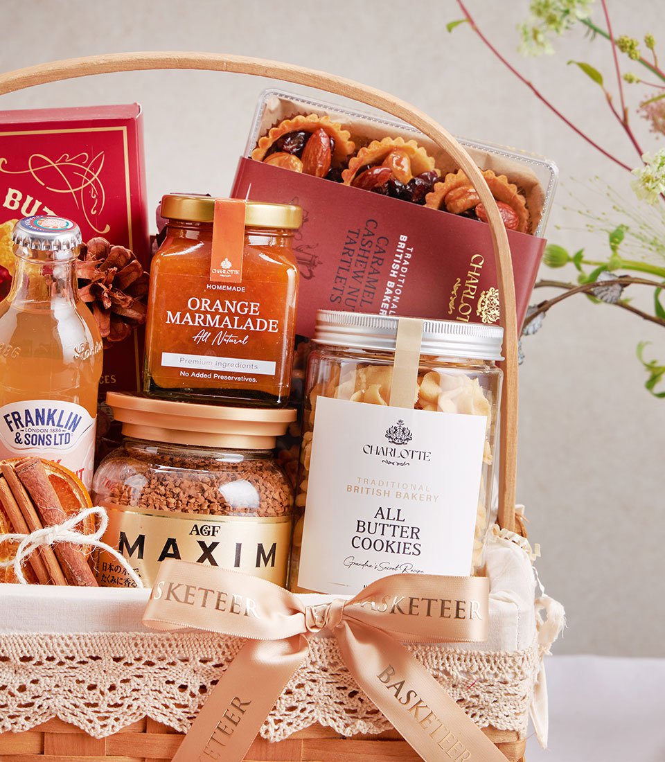Wicker gift basket with raspberry cookies, lychee honey, chocolate gourmet items, dried citrus and cinnamon accents