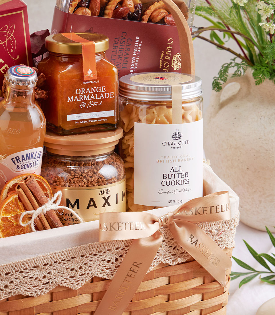 Premium gourmet gift basket with raspberry cookies, lychee honey, chocolate, and artisan British baked goods in woven wicker