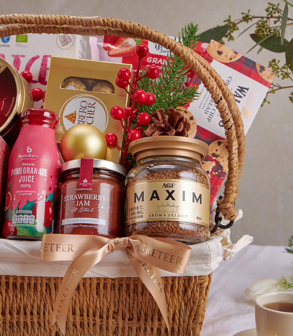 Woven gift basket with strawberry jam, gourmet chocolates, pomegranate juice, and coffee, tied with gold ribbon