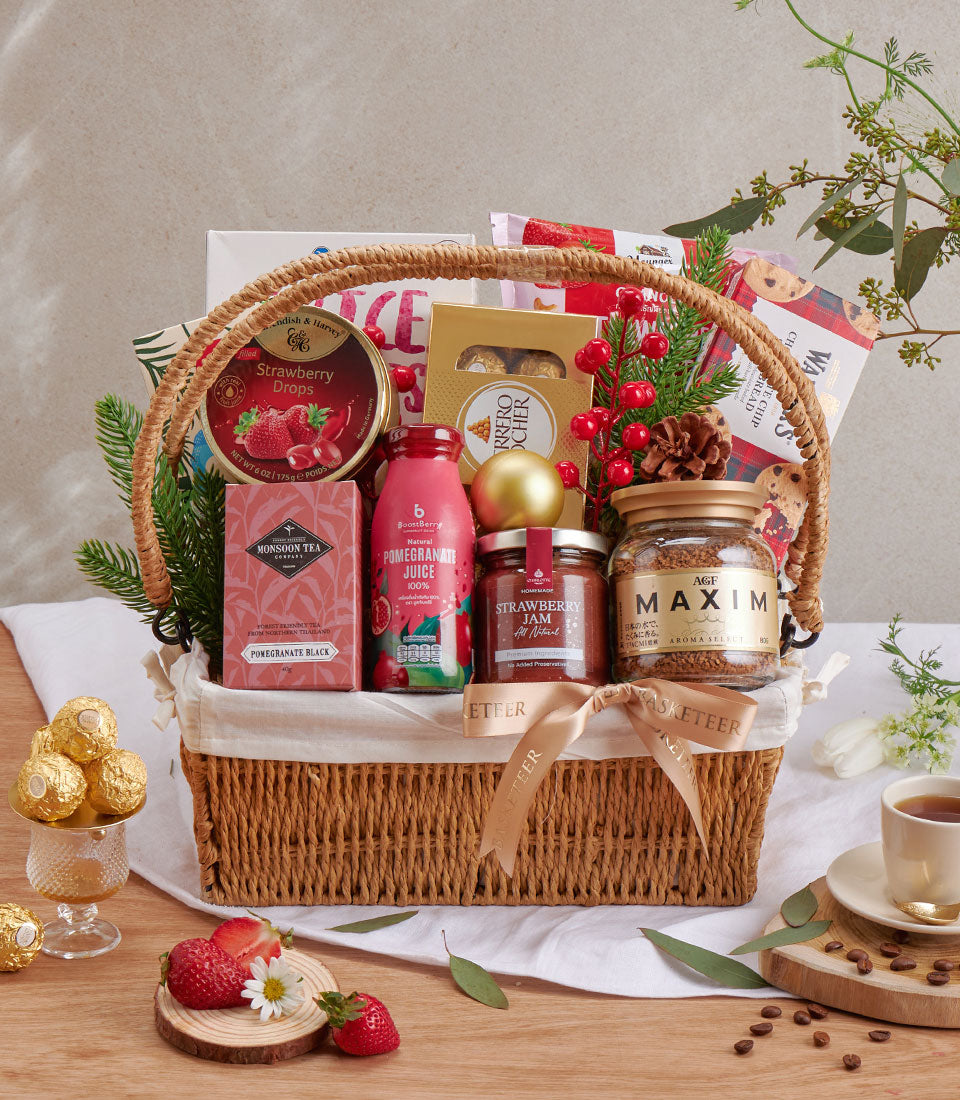Luxury wicker gift basket with strawberry jam, gourmet chocolates, coffee, and festive holiday trimmings in red and gold
