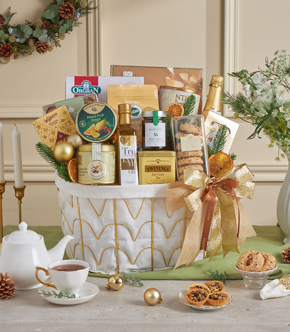Gold wire basket filled with gourmet treats, olive oil, tea, and champagne, tied with gold ribbon for New Year celebrations