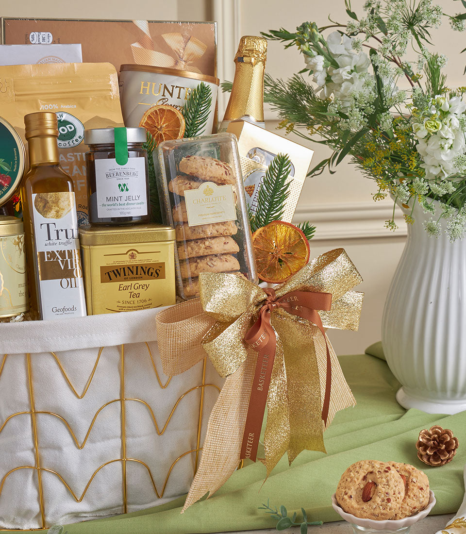 Gold-toned gourmet gift basket with coffee, olive oil, tea, chocolates, and sparkling wine for New Year celebrations