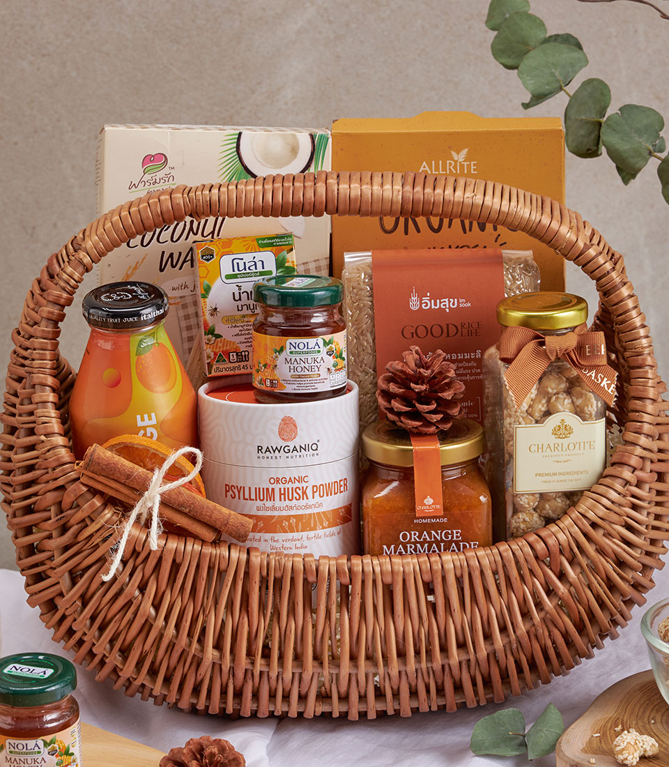 Woven wicker wellness gift basket with organic honey, psyllium husk, orange juice, and gourmet pantry essentials