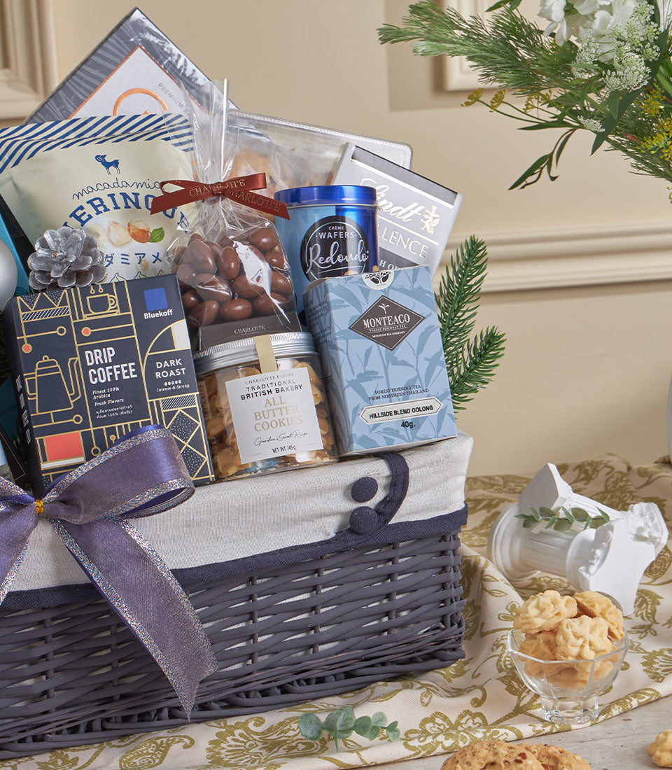 Dark grey woven luxury gourmet gift basket with premium coffee, chocolates, cookies and tea, tied with purple ribbon for New