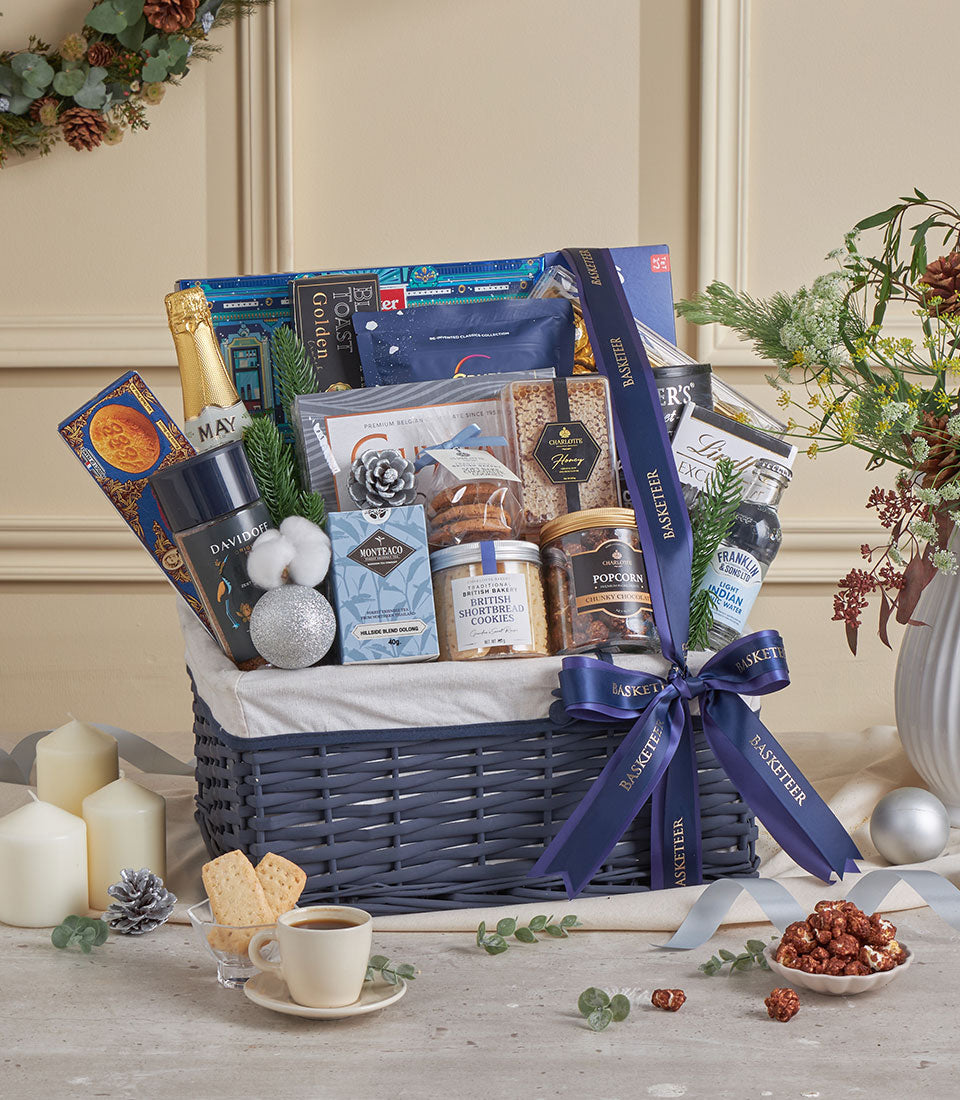 Blue woven luxury gift basket with champagne, gourmet treats, and festive decor for New Year celebrations
