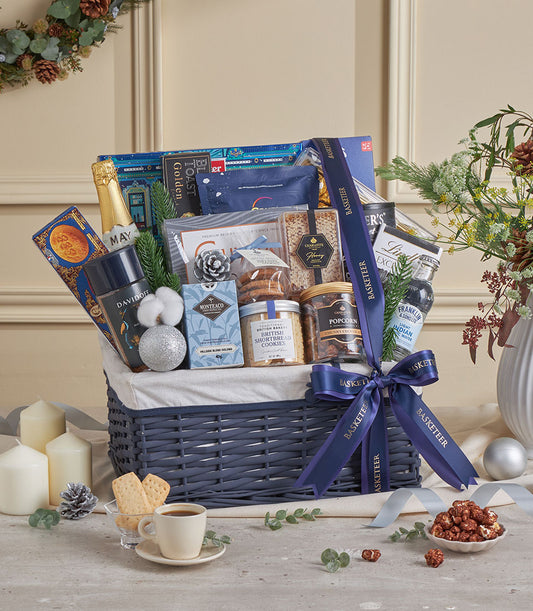 Blue woven luxury gift basket with champagne, gourmet treats, and festive decor for New Year celebrations